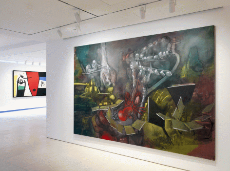 Installation view of Masterworks. This image shows a large scale painting by Roberto Matta and in the background a chunk of a painting by Joan Miro.